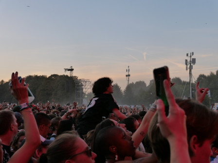 Une personne hissée sur les épaules d'une autre, en concert, qui reçoit la musique comme si elle était écrite pour lui.