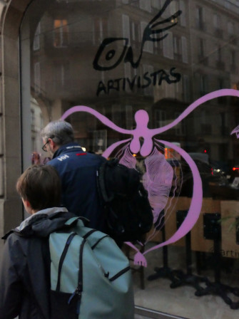 Un père et son fils passent, indifférents, devant l'image d'une vulve représentée sur une vitrine du 9e arrondissement.