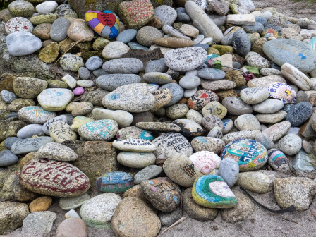 Des galets peints de dessins et de prénoms, posés au pied de la "Croix des amoureux" (Lesconil, Finistère)