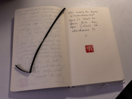 Mon carnet Moleskine plus complètement neuf, avec écrit sur la page : "Non mais tu crois sérieusement que je vais te faire lire ce que j'écris ici ? :)" suivi de mon sceau.