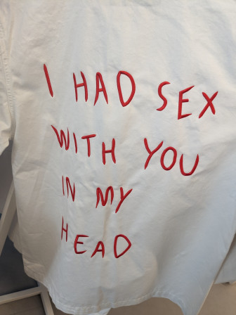 Une chemise blanche sur un portant avec, écrit en caractères rouges dans le dos : "I had sex with you in my head